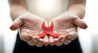 © Arifkki - Hope and Awareness: Hands Gently Holding a Red Ribbon Symbolizing Solidarity and Support for AIDS and HIV Prevention, A Powerful Reminder for Compassion