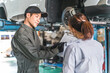© buritora - A female customer and a male mechanic receive an explanation about a car that has been lifted for a vehicle inspection