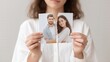 © StockHero - Woman holding torn photographs of couple, symbolizing emotional distress and heartbreak during divorce, with soft background and neutral tones, conveying a sense of loss and separation