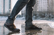 © diy13 - Boots standing on icy ground, illustrating the danger of slipping on a frozen, slippery winter surface. man walks cautiously along an icy street on a winter day for fear of slipping and falling.