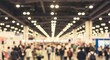 © sajibul35 - Blurred view of a large, crowded convention hall or trade show floor with many people attending and bright overhead lighting creating a bokeh effect