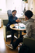 © Maskot - Smiling male counselor shaking hands with teenage boy while sitting in high school office