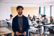 © Maskot - Portrait of smiling male high school teacher standing in classroom