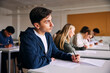 © Maskot - Contemplative teenage boy looking away while sitting for educational exam in high school classroom