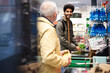 © Maskot - Smiling man talking with senior male while shopping in grocery store