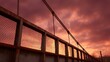 © Bussakon - Dramatic crimson sunset over a weathered industrial bridge railing