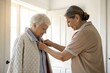 © IrenKa - Adult helping senior put on quilted jacket in bright home setting, showing care, dignity, and everyday support with warmth and empathy