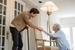 © IrenKa - Young man and elderly woman share a warm moment of connection and care in a sunlit room, highlighting intergenerational support and love