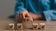 © Omid studio - Ethical Assessment Concept. Placing wooden blocks with icons including checkmarks and a symbol of ethics, representing the evaluation and validation of ethical standards. Effective compliance.