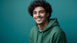 © Bernd Schmidt - Young man curly hair green hoodie smiling turquoise background cheerful playful portrait right side generative AI