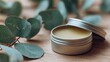 © Asayamrad - A soothing balm container beside fresh eucalyptus leaves on a wooden surface.