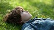 © Formoney - A boy relaxes on green grass looking thoughtfully at the blue sky above in a peaceful park.