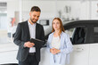 © Serhii - Salesman assisting female customer in car showroom