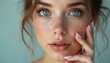 © miss irine - Beautiful woman with blue eyes, freckles gently touches perfect face. Young female healthy skin, natural makeup. Girl with long eyelashes, french manicure advertises cosmetics spa treatment in beauty