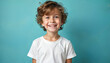 © miss irine - Young happy boy with curly hair smiles at camera. Child wears white tee shirt on blue studio background. Kid wide joyful expression, showing teeth. Little person poses for portrait for bright ad