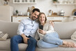 © fizkes - Loving couple cuddle on comfy couch take selfie using phone