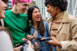 © Xavier Lorenzo - Multiracial friends laughing and having fun while using mobile phones, browsing social media together.