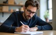 © fu - Man Wearing Glasses Writes Notes in His Notebook. High quality