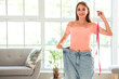 © Pixel-Shot - Beautiful young woman in loose jeans with measuring tape at living room. Weight loss concept