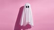 © mila103 - A playful homemade ghost costume stands against a bright pink background featuring two large black eye holes. This fun decoration adds a cheerful touch to Halloween festivities.