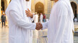 © Анастасия Терентьева - Two muslim men in white traditional clothes shaking hands near mosque