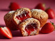 © lam - a close-up of a stack of three strawberry muffins with the top one cut in half, revealing the strawberry jam filling, and a half strawberry on the side, all set against a red background.