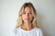 © Vadym - Blonde woman in white t-shirt looks forward with calm expression. Studio portrait with plain white background. Natural light illuminates face, shoulders. Casual, simple, clean indoor shot. Posing for