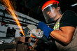 © YanlethRivera - Close-up of a man using a grinder on an anvil. Close-up of an angle grinder cutting metal on a workbench