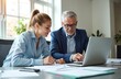 © Vadym - Senior businessman, young woman discuss project on laptop. Two professional colleagues work together in modern office. Collaborate on finance strategy, share ideas, plan company success. Mentor
