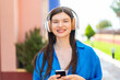 © luismolinero - Young pretty woman at outdoors listening music with a mobile and looking front