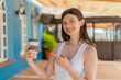 © luismolinero - Young pretty Ukrainian woman holding a take away coffee at outdoors and pointing it