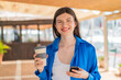 © luismolinero - Young pretty woman at outdoors using mobile phone and holding a coffee with happy expression