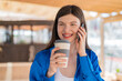 © luismolinero - Young pretty woman at outdoors using mobile phone and holding a coffee with happy expression