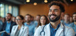 © Vadym - Smiling male doctor in white coat with stethoscope listens attentively at medical conference. Diverse group of healthcare professionals learn new skills during lively seminar. People attend important