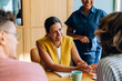 © (JLco) Julia Amaral - Smiling woman discussing ideas with colleagues around a table