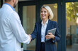 © Vadym - Smiling businesswoman shakes hands with doctor outdoors. Female sales rep meets male medical pro. Discuss healthcare business, new products, pro collaboration, building trust for industry