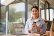 © Tj - Young woman enjoying coffee while working remotely at cafe