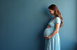 © Pete - Smiling pregnant woman in light blue dress cradles her belly. Expectant mother experiences joy anticipation of new life. Healthcare wellness concept.