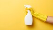 © Intellectual - Top view photo of hand in yellow rubber glove using spay detergent white bottle without label on isolated yellow background with blank space