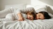 © BoldStock - Caucasian female adult and child sleeping on bed in morning light