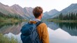 © iuricazac - Man standing near lake, mountains in background, backpack on back, outdoor setting.