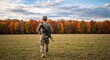 © Vasiliy - Soldier in camouflage walking in a field towards an autumn forest. Military service member on duty with a rifle. Veteran and patriotism concept