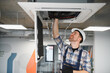© Serhii - Hvac technician repairing air conditioning unit on ceiling