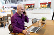 © Jelena - Mature man talking on phone enjoying cafe atmosphere