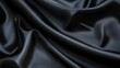 © somchaichoosiri - Black silk fabric draping elegantly on a surface showcasing its smooth texture and sheen
