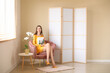 © Pixel-Shot - Young woman with magazine sitting in armchair in room