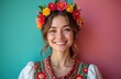© Maryna - Woman in ethnic dress. Smiling girl with flower crown poses in green pink background. She wears traditional hungarian clothing with floral embroidery. Model shows folk beauty, culture and style.