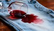 © Evarelle - A glass of red wine spilled on light blue denim jeans creating a stain. Accidental mess on clothing and fabric. Housework and laundry problem concept