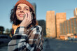 © SHOTPRIME STUDIO - Woman phone smile city beanie coat golden hour: candid lifestyle portrait of a smiling young woman on a mobile call in urban street at sunset, authenticity and emotional storytelling vibe.