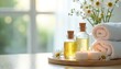 © Maryna - Spa setup with essential oil bottles, lit candles, white towels on wooden tray. Daisies decorate arrangement creating relaxing wellness atmosphere. Natural light from window brightens health care